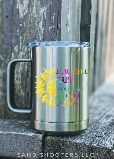 Photo of a silver 15 oz tumbler with handle and color printed image of a sunflower and text that reads "Beautiful girl, you can do hard things."